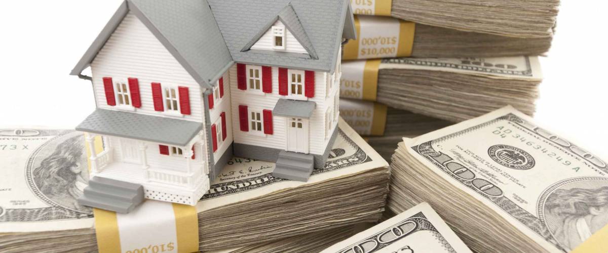 Small House with Stacks of Hundred Dollar Bills on White.