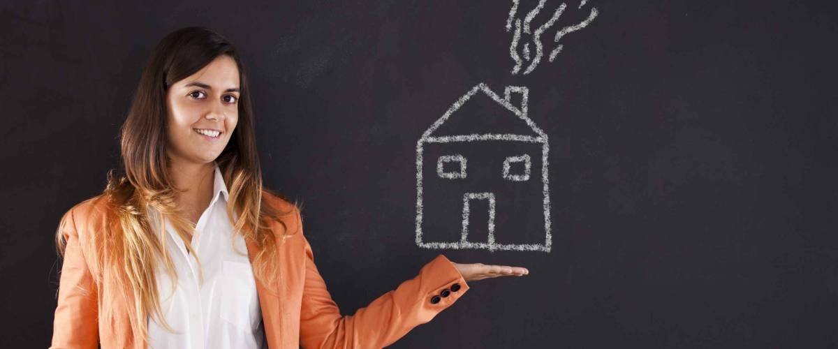 Happy woman showing a house drawing in the chalkboard