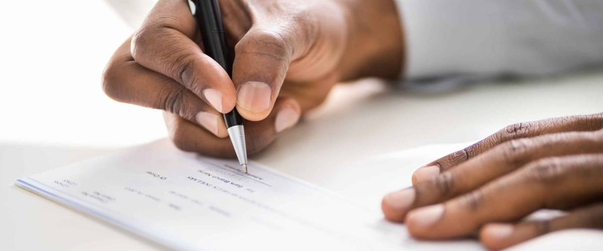 Close up of person's hands writing a check