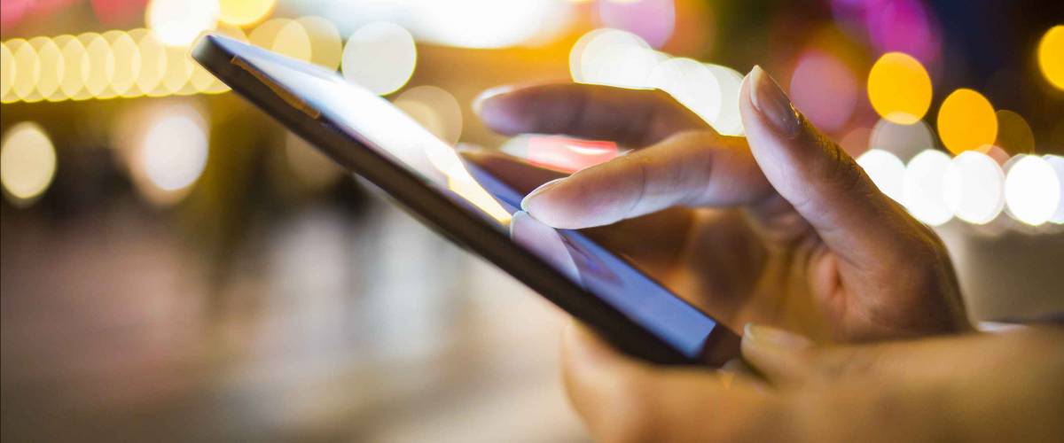 Woman using her Mobile Phone in the street, night light Background