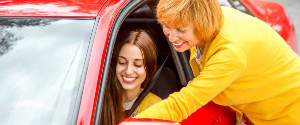 Mother with her daughter near red car
