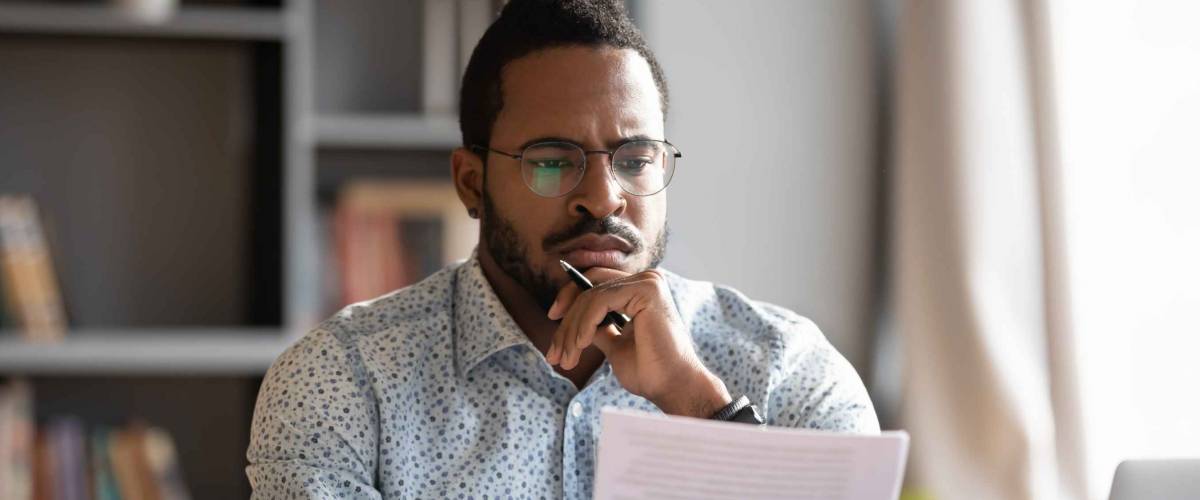 Young man looking intently at paper, hand to chin
