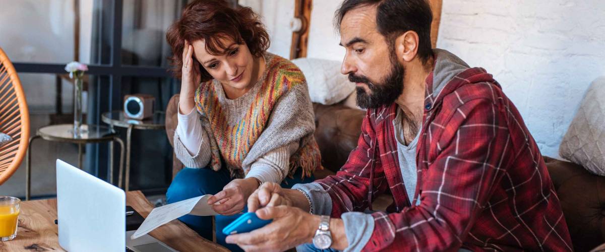 Couple sitting on their couch looking at laptop and bils