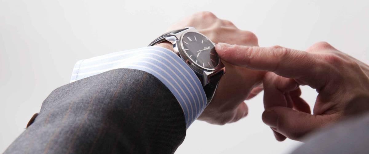 Businessman look his watch, isolated on a grey background