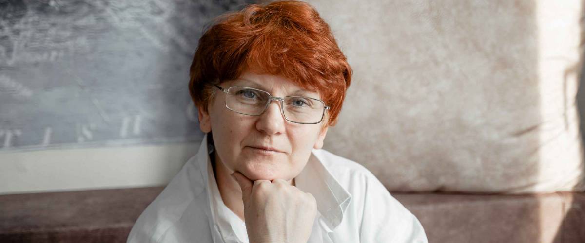 Worried older woman in glasses with red hair.