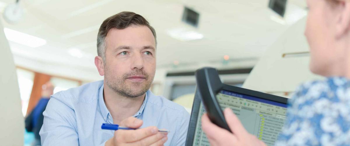 Man talking to woman who is back facing to camera about something on a piece of paper