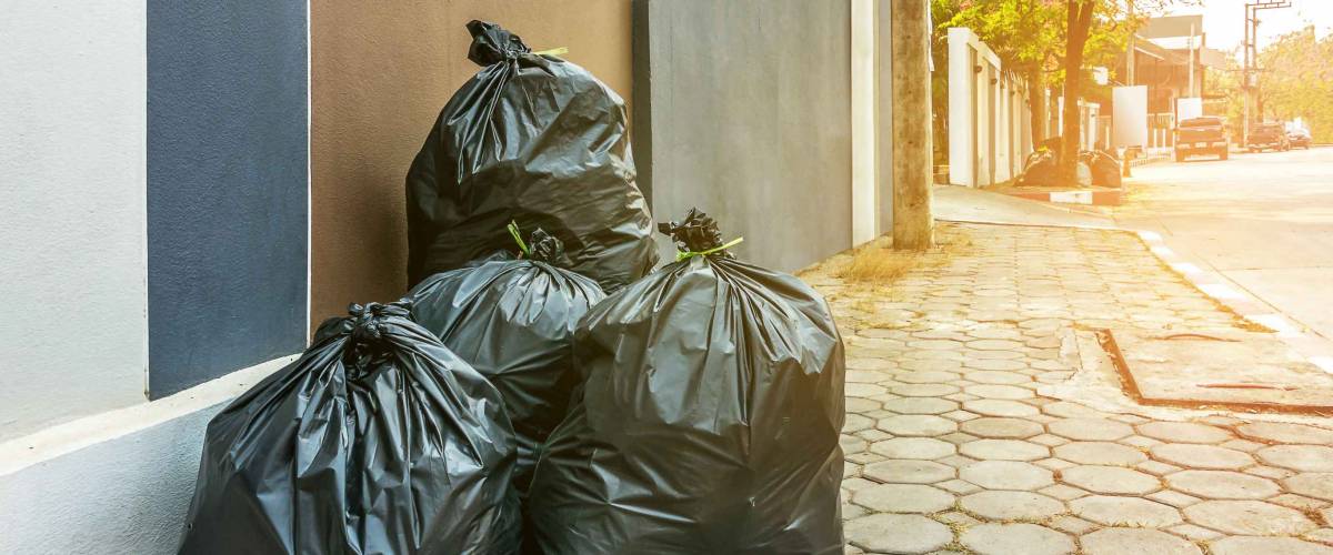 Pile of black garbage on the footpath at side road in big city, pollution trash