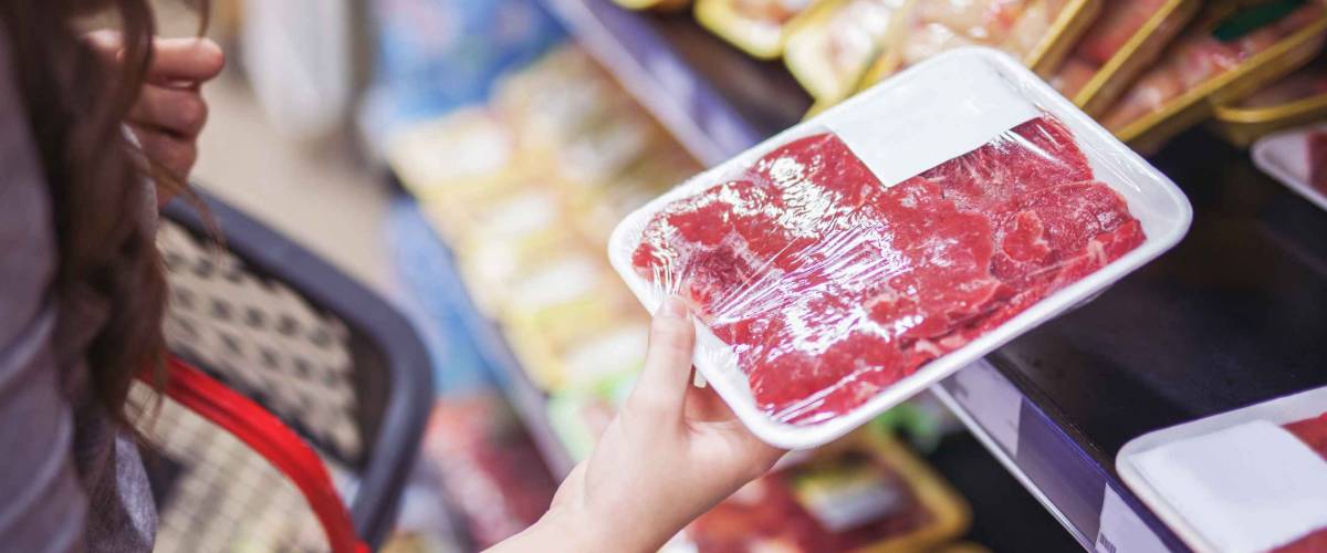 Close up of woman holding wrapped meat in grocery store