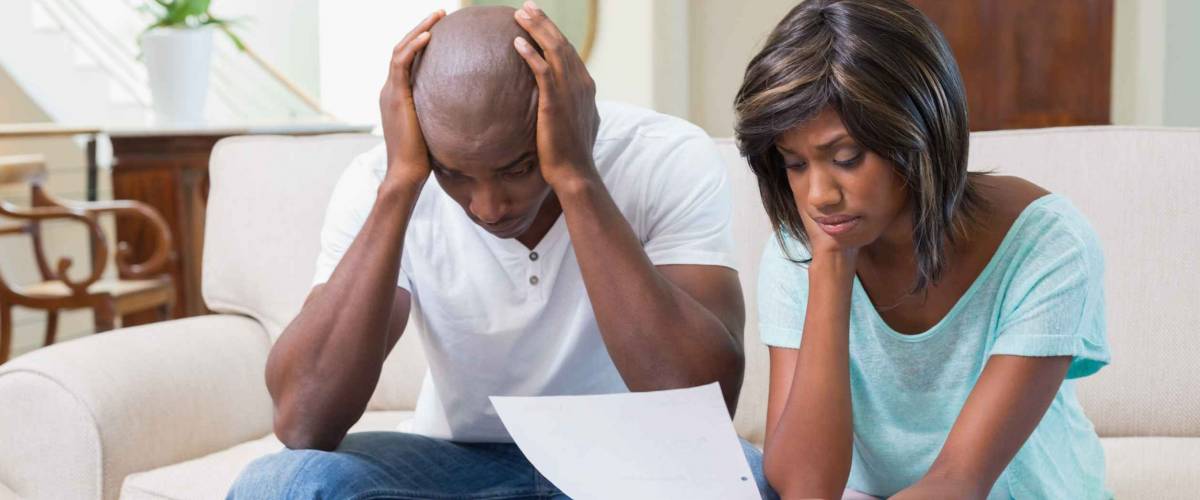 Stressed couple calculating bills on the couch at home in the living room