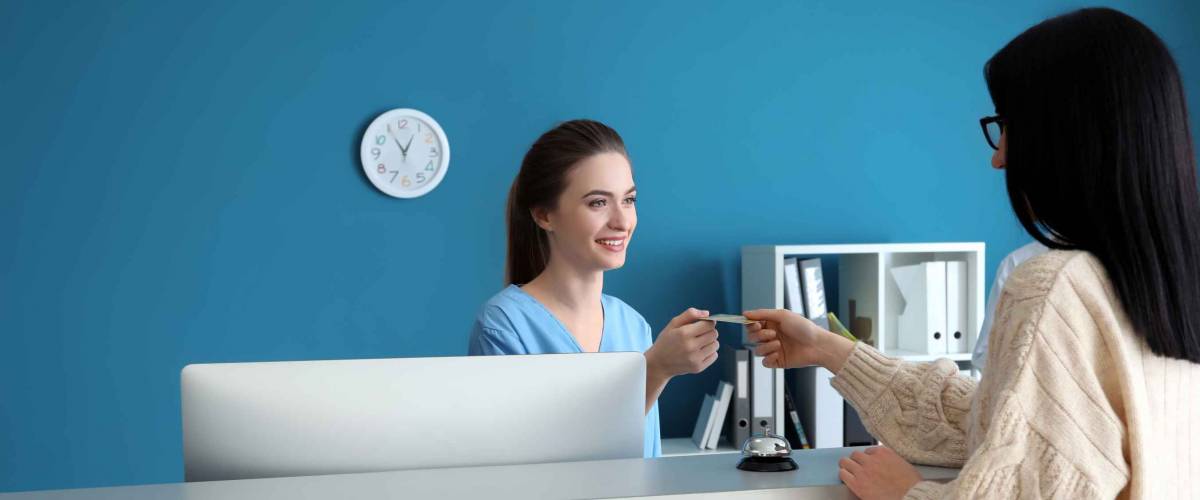 Female receptionist receiving payment for medical service from patient in clinic