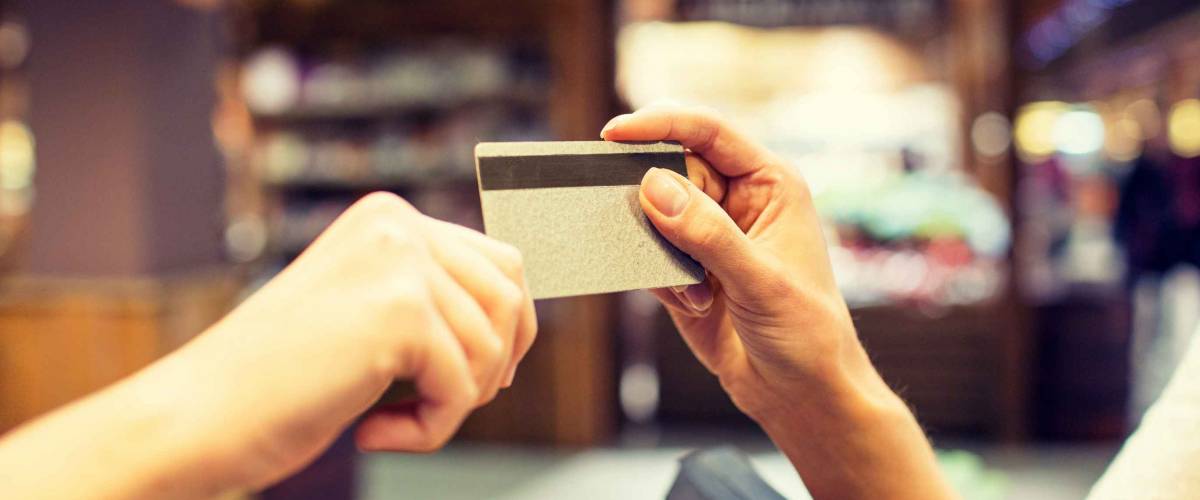 sale, shopping, payment, consumerism and people concept - close up of hands giving credit card at checkout in market or mall
