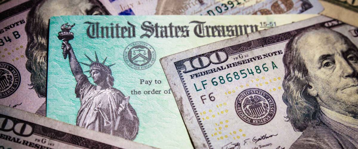 WASHINGTON DC - APRIL 2, 2020: United States Treasury check with US currency. Illustrates pandemic stimulus check payment.