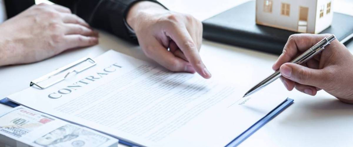 Estate agent broker pointing contract form to client signing agreement