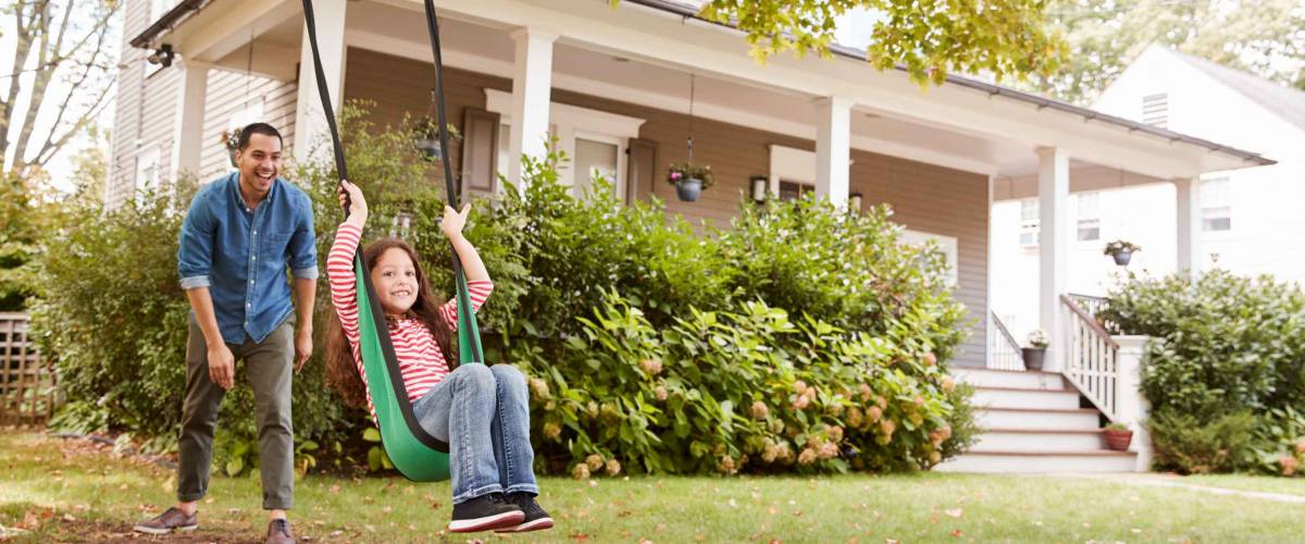 Father Pushing Daughter On Garden Swing At Home