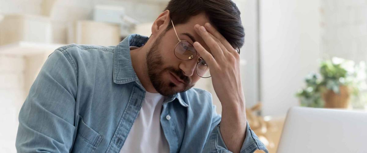 Upset frustrated young man reading bad news about his student loan debt
