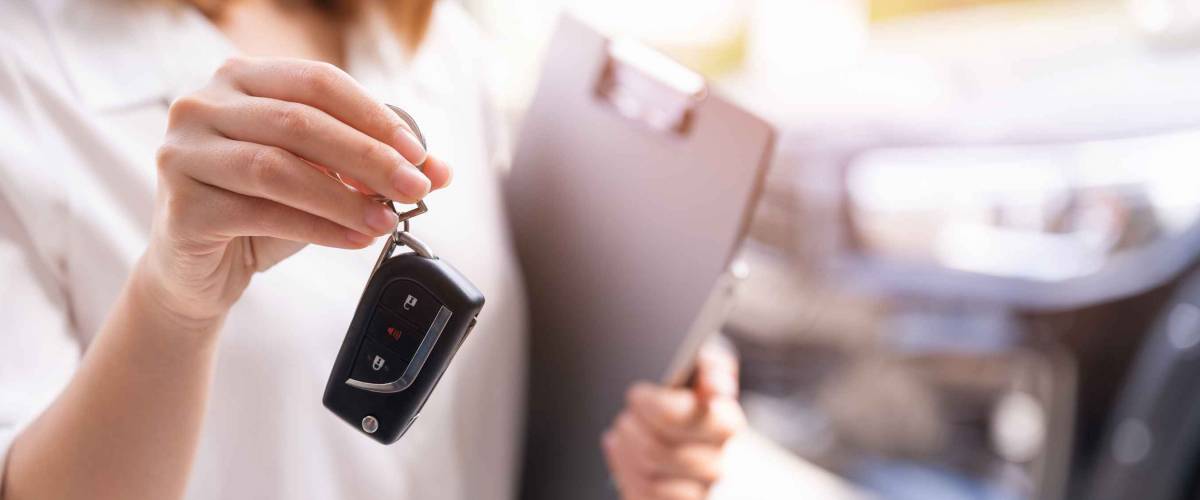 Woman holding set of keys for a car with clipboard in hand