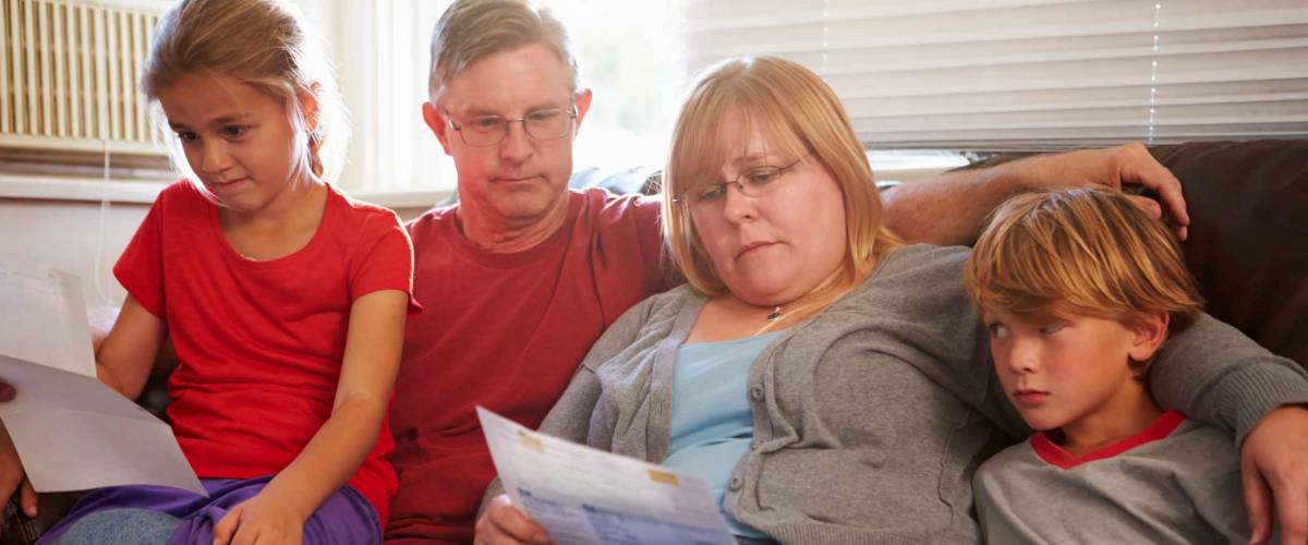 Unhappy Family Sitting On Sofa Looking At Bills