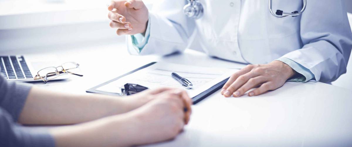 Close up of doctor going over forms with patient across the table from them.