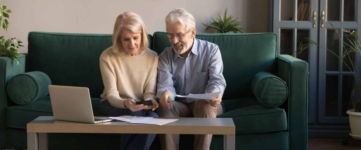 Smiling contemporary senior couple spouses use laptop