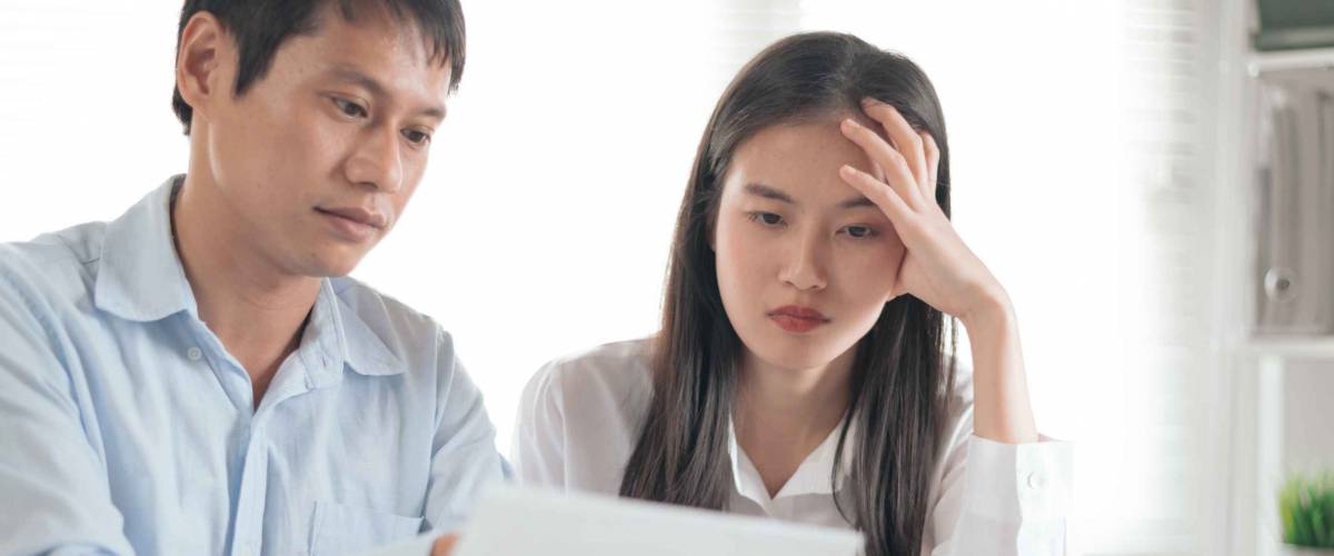 Young couple looking at a sheet of paper, looking concerned