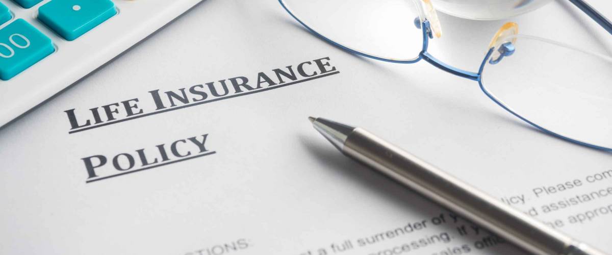life insurance policy on a piece of paper, with pen, calculator and glasses on top