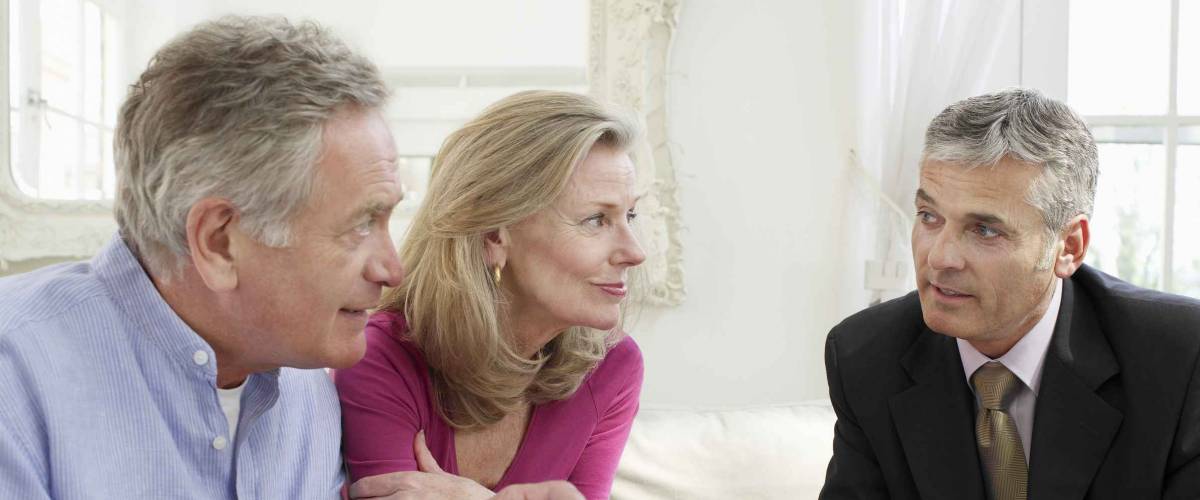 Mature couple sitting on sofa with financial advisor