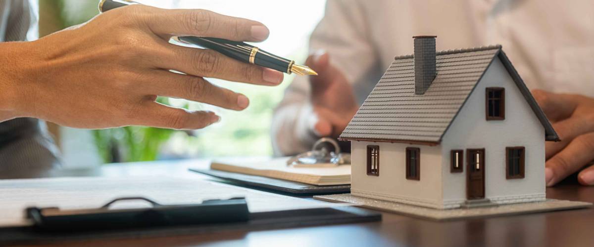 House model with agent and customer discussing for contract to buy, get insurance or loan real estate or property.