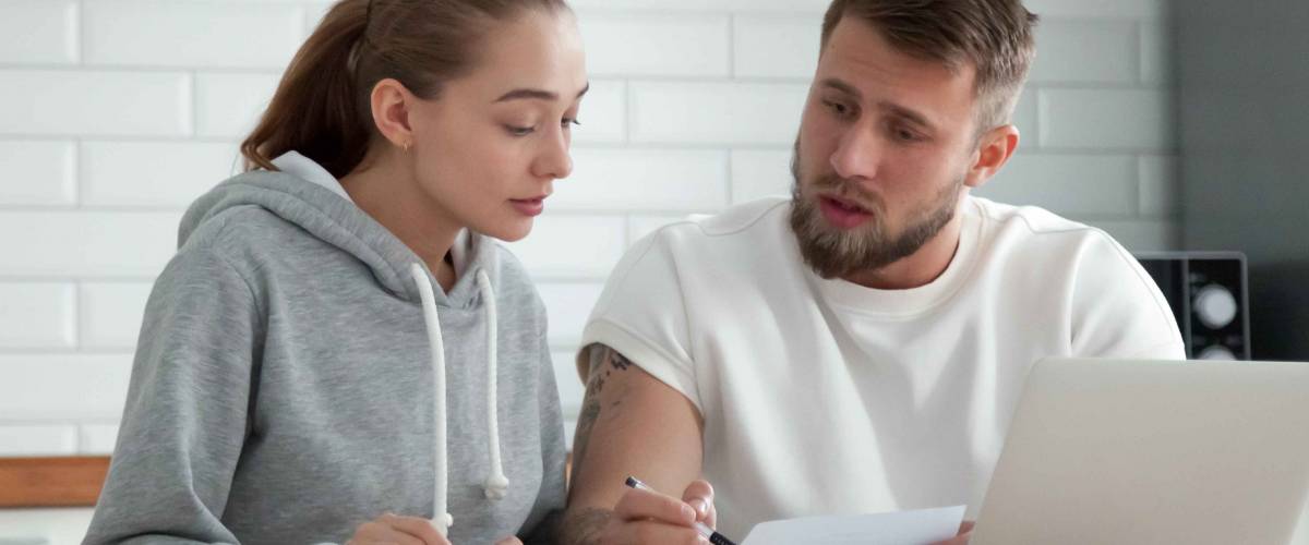 Millennial couple sitting at table looking for a lower mortgage rate.