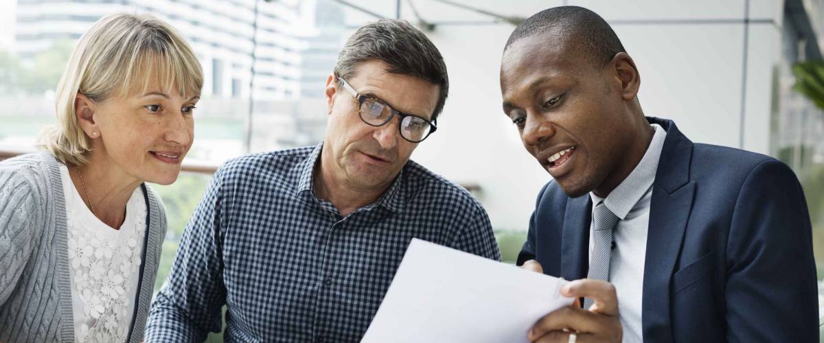 Man in suit showing older couple something on a piece of paper