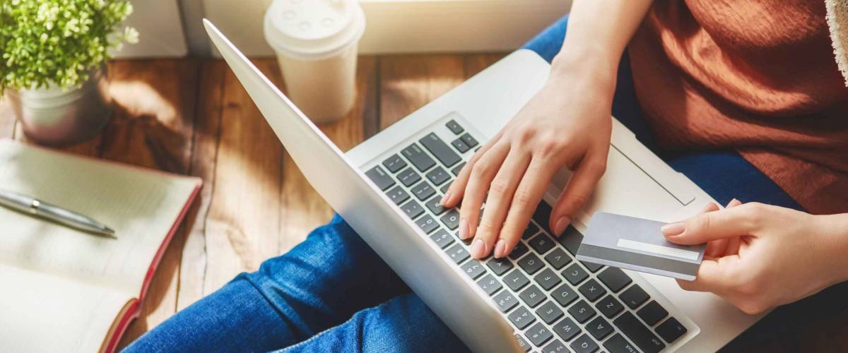 Woman is holding credit card and using laptop computer. Online shopping concept. Close up.