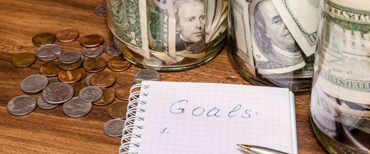 New years resolutions with dollar in glass jar, coins on wooden table