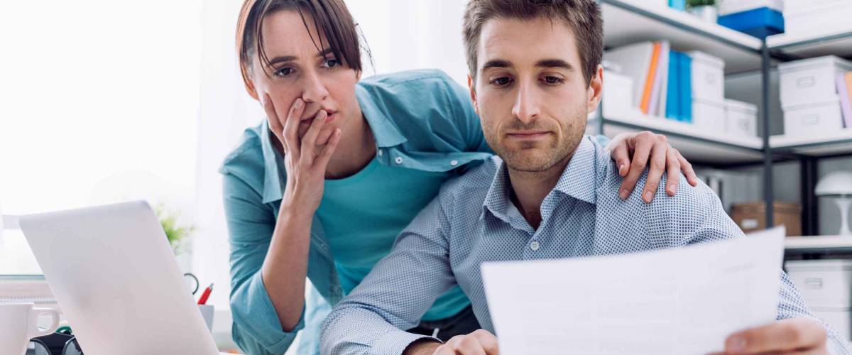 Young affectionate couple at home checking expensive bills, they are calculating balance and costs