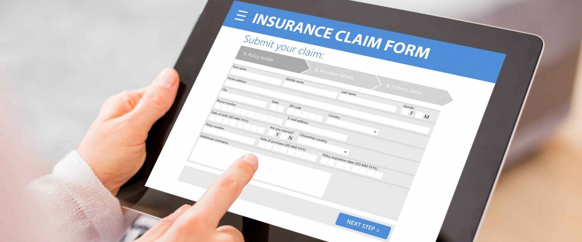 Man holding a tablet with insurance claim form open on it.