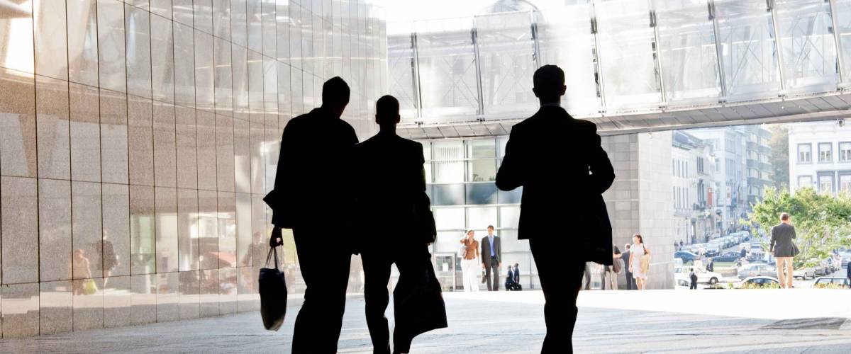 Three business people walking down the street talking. Silhouettes. Motion Blur.