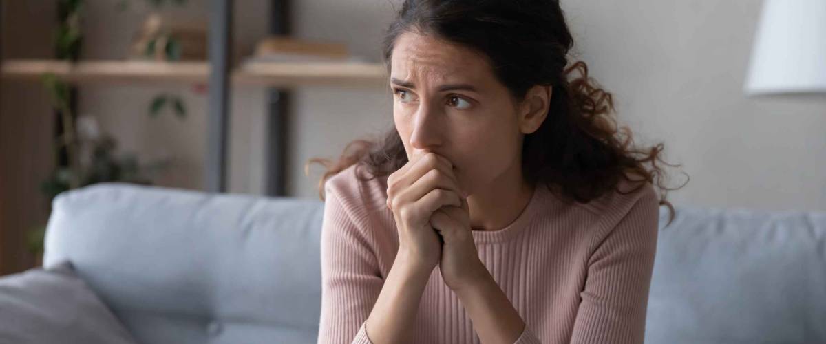 Nervous young woman sitting on sofa