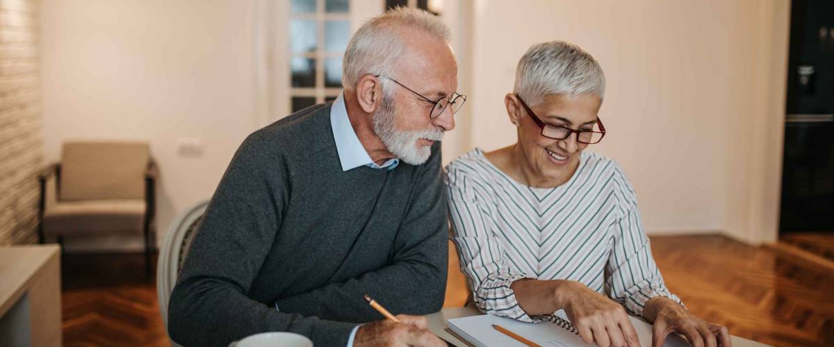 A happy senior couple calculating their finances in a beautiful home.