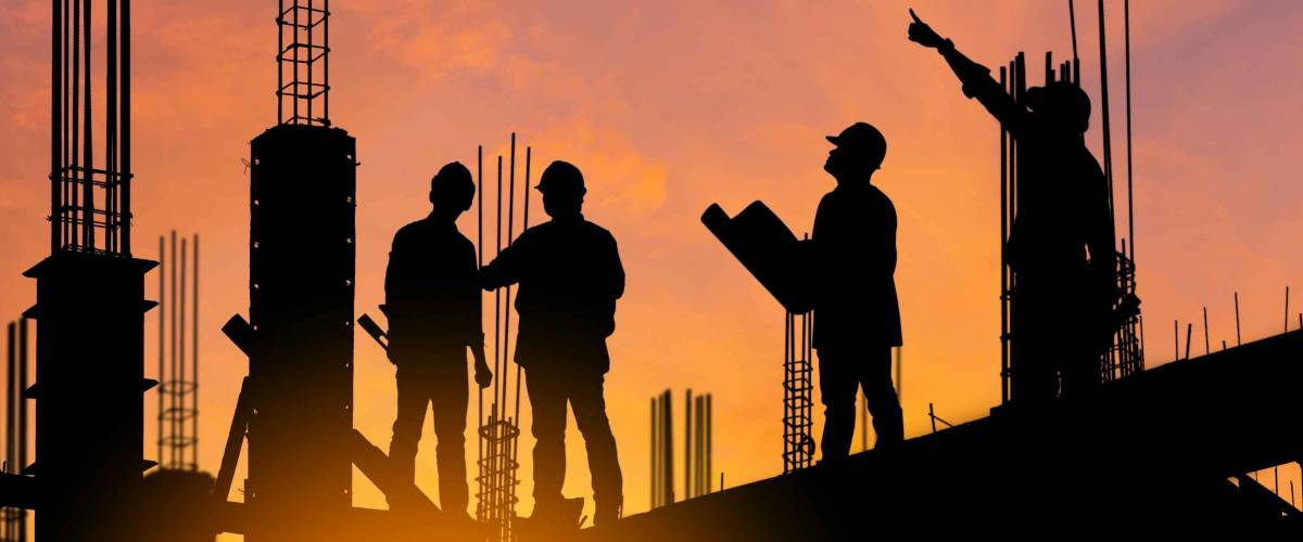Silhouette of Engineer and worker on building site, construction site at sunset in evening time.