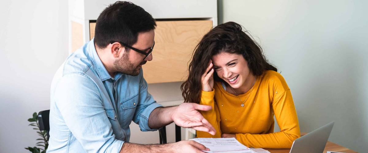Close up of couple talking, looking at documents while sitting at a table.