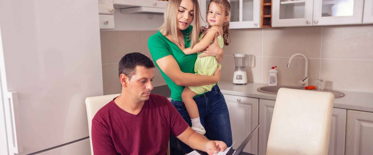 young smiling parent calculating bills at home