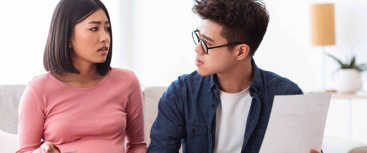 Bankruptcy. Asian Family Couple Struggling Financial Crisis Calculating Their Expenses And Bills Not Able To Pay Debts Sitting On Couch At Home. Finance Problems, Coronacrisis Concept