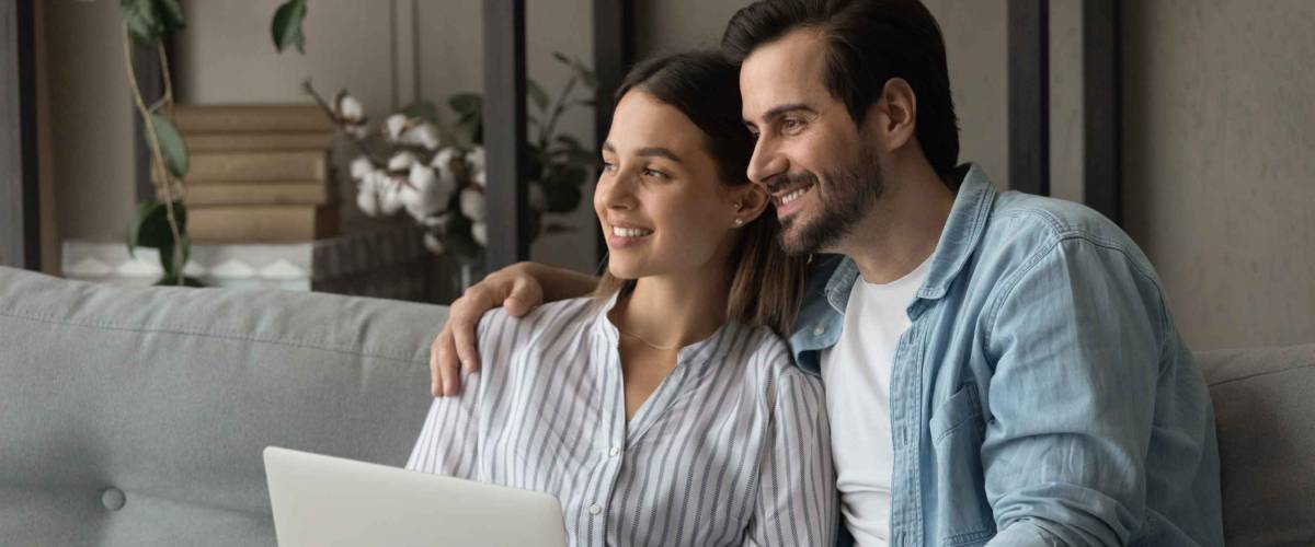 Dreamy family couple cuddle on couch distracted from