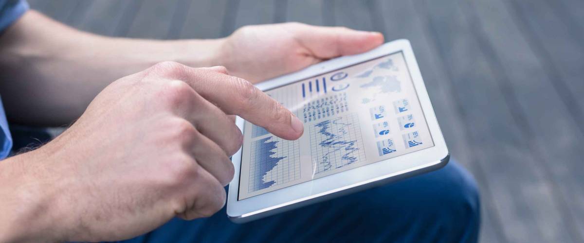 Casual person using digital tablet computer to analyze a financial dashboard with charts.