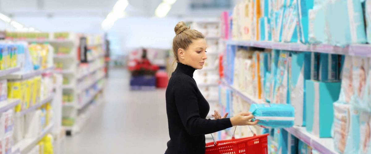 Woman shopping in supermarket in diaper aisle.
