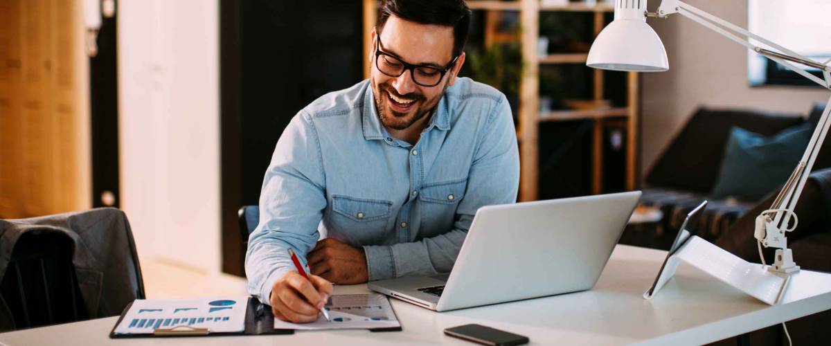 Young business man working at home with laptop and papers on desk