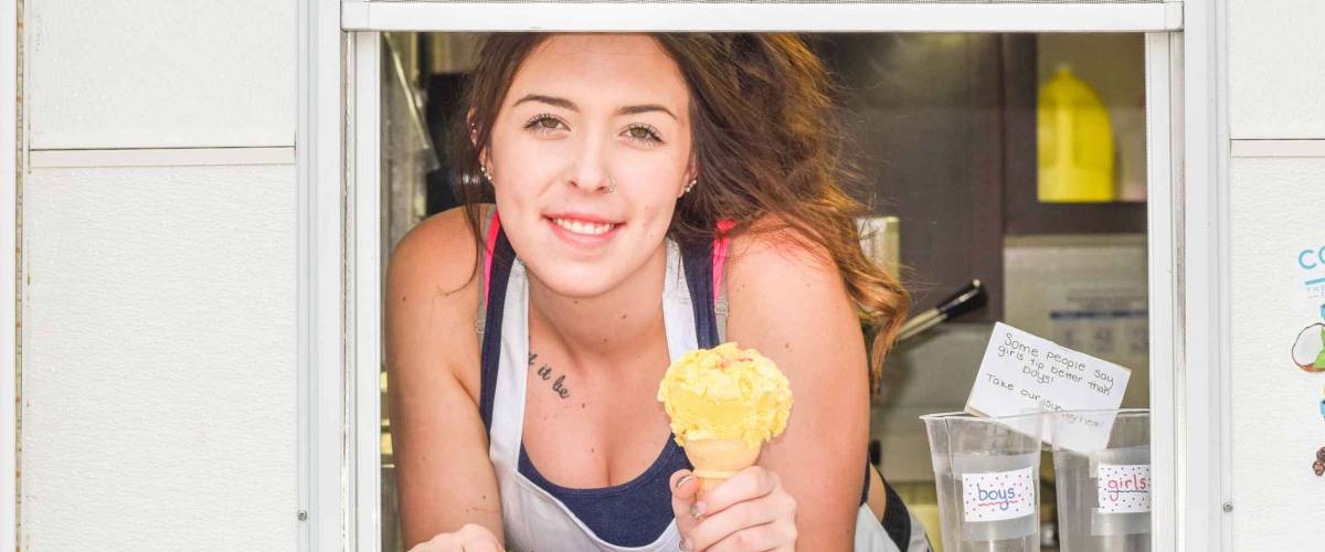 girl holding an ice cream out a takeout window.