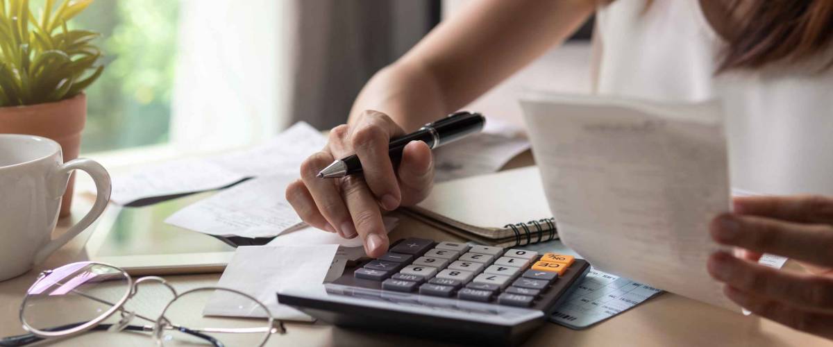 Close up of young woman using calculator and looking at receipts.