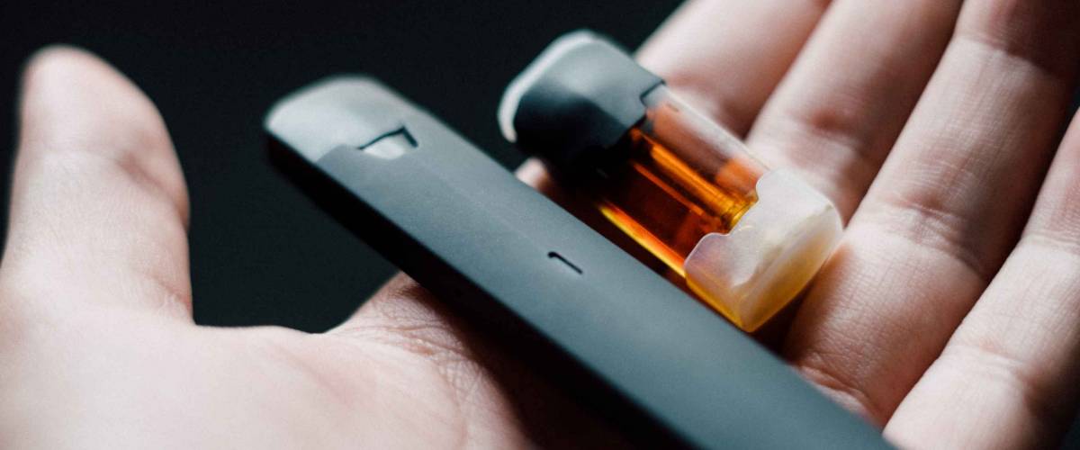 Disposable vape pen with refill pod in a hand.
