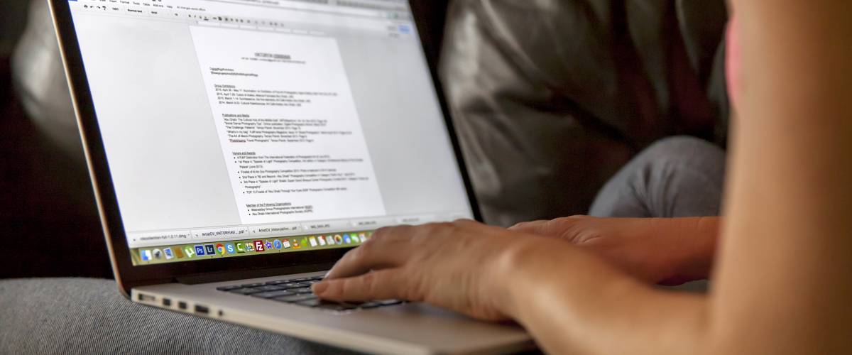 Person sitting on computer, writing a resume.
