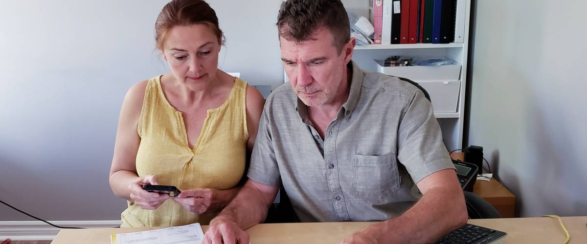 Couple look stressed, planning finances at their kitchen table.