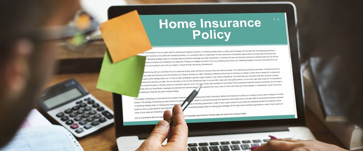 Two people looking at a laptop screen that says Home Insurance Policy.